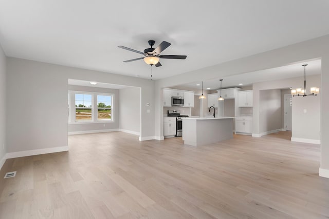 unfurnished living room with baseboards, visible vents, a sink, and light wood-type flooring