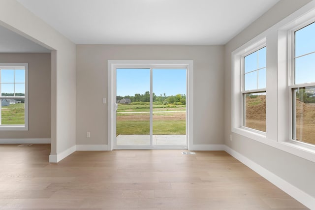 empty room with baseboards, light wood finished floors, and visible vents