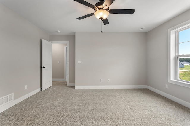 unfurnished room with plenty of natural light, light carpet, a ceiling fan, and visible vents