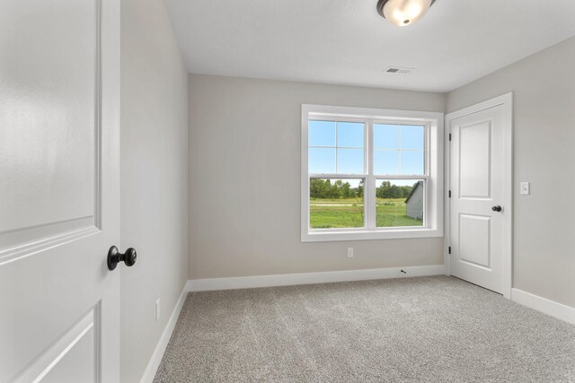 unfurnished room featuring baseboards, light carpet, and visible vents