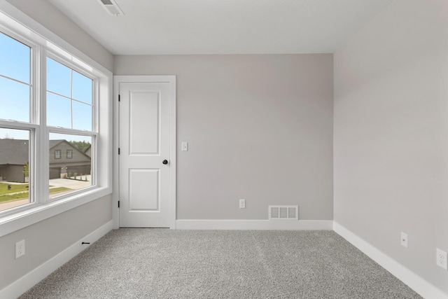 carpeted spare room featuring visible vents and baseboards