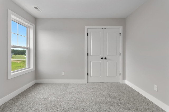 unfurnished bedroom with a closet, baseboards, carpet flooring, and visible vents