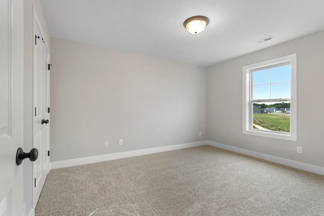 carpeted empty room featuring baseboards and visible vents