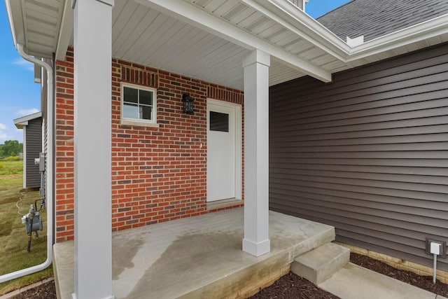 doorway to property featuring brick siding, a shingled roof, a chimney, and a porch