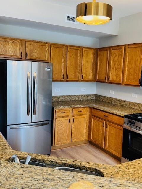 11246 Bellflower Ln, Huntley, IL 60142 - kitchen with brown cabinetry, light stone countertops, and stainless steel appliances