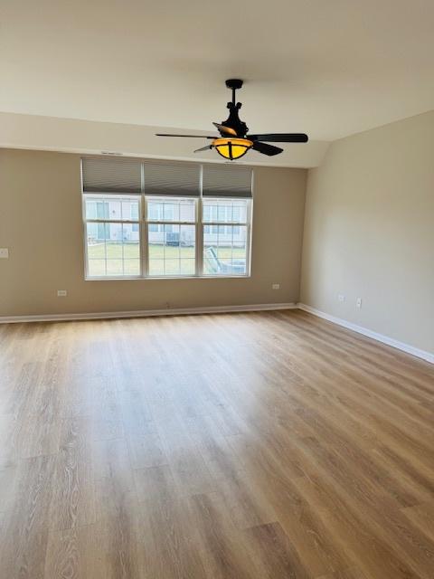 11246 Bellflower Ln, Huntley, IL 60142 - empty room featuring a ceiling fan, wood finished floors, and a healthy amount of sunlight