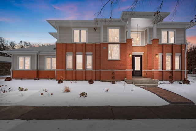 snow covered property featuring brick siding