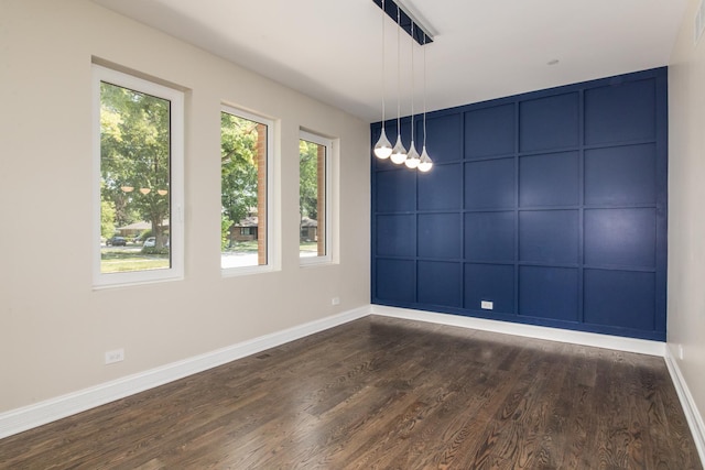 unfurnished room with a decorative wall, baseboards, and dark wood-style floors