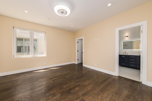 spare room featuring a sink, baseboards, dark wood finished floors, and recessed lighting