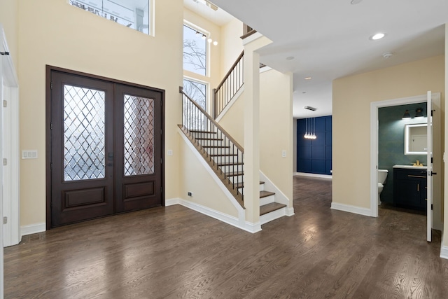 foyer entrance with french doors, baseboards, wood finished floors, and stairs