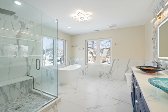 full bathroom with a marble finish shower, tile walls, a wainscoted wall, and a healthy amount of sunlight