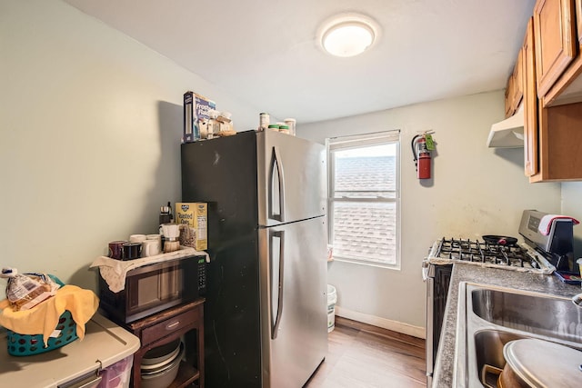 8151 S Bennett Ave, Chicago, IL 60617 - kitchen featuring brown cabinetry, a sink, baseboards, stainless steel appliances, and light wood-style flooring