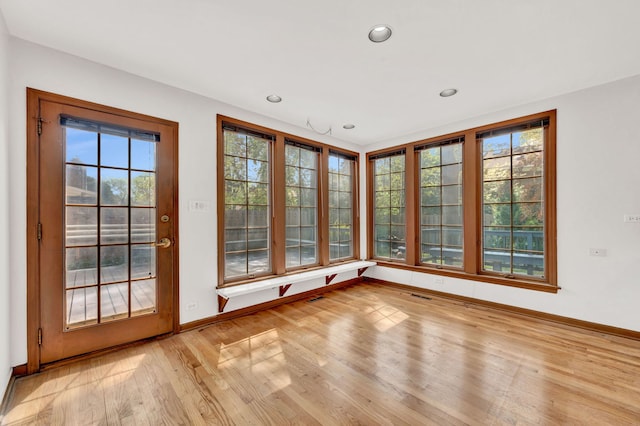 unfurnished sunroom featuring baseboards, wood finished floors, and recessed lighting