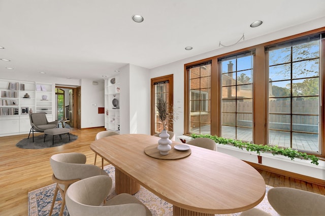 dining room featuring healthy amount of natural light, recessed lighting, light wood-style flooring, and built in shelves