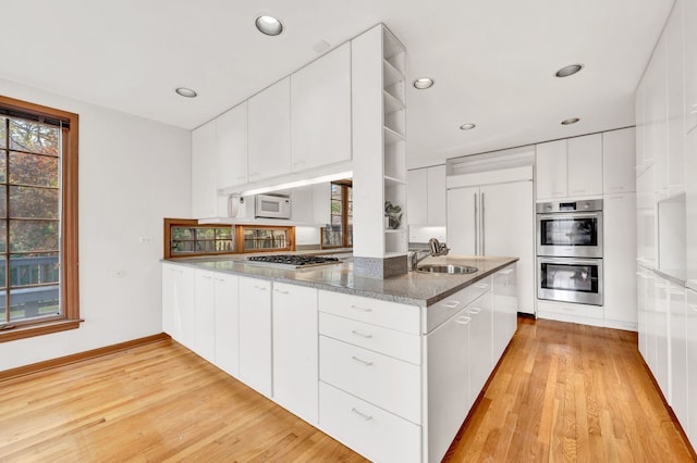 kitchen featuring stainless steel appliances, open shelves, light wood finished floors, white cabinetry, and recessed lighting