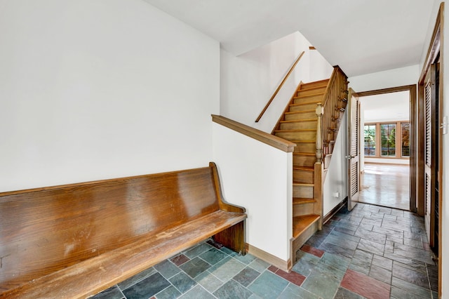 stairway featuring stone tile floors and baseboards