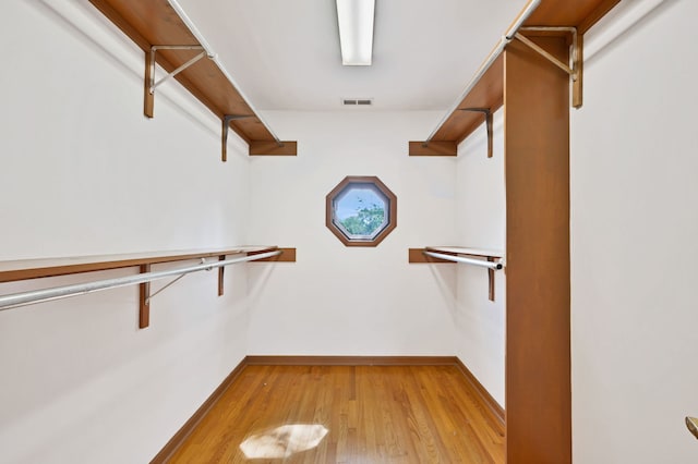 walk in closet with light wood-style flooring