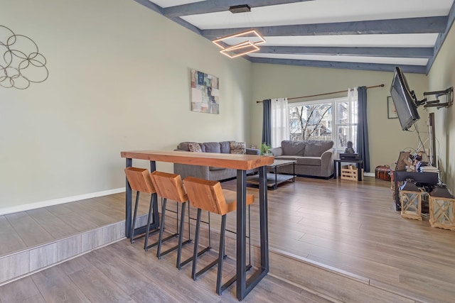 dining area featuring baseboards, wood finished floors, and lofted ceiling with beams