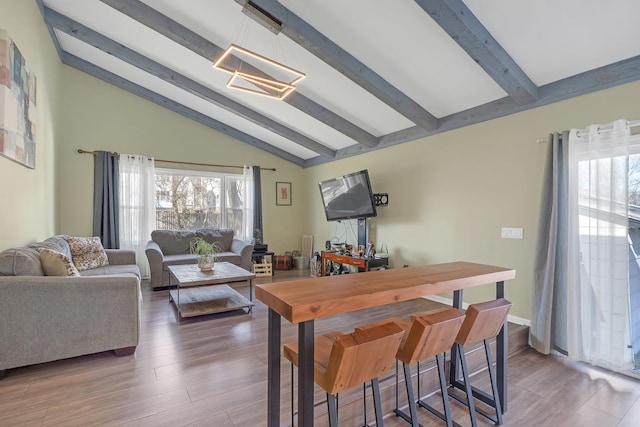 dining area with wood finished floors and lofted ceiling with beams