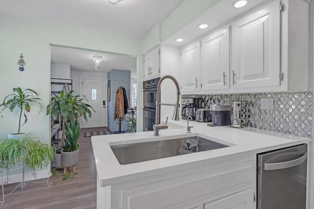 kitchen featuring white cabinets, a sink, dark wood-style flooring, appliances with stainless steel finishes, and backsplash