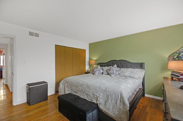 bedroom featuring visible vents, a closet, baseboards, and wood finished floors