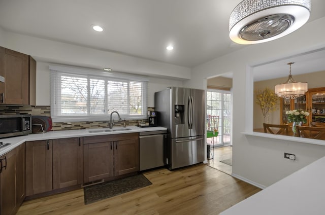 kitchen featuring a sink, backsplash, light countertops, and stainless steel appliances