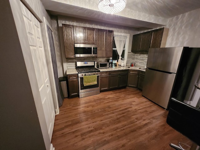 1022 N Rockwell St, Chicago, IL 60622 - kitchen with dark brown cabinets, light countertops, stainless steel appliances, decorative backsplash, and dark wood-style floors