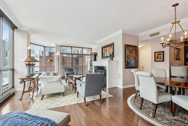 living room featuring visible vents, hardwood / wood-style flooring, baseboards, an inviting chandelier, and ornamental molding