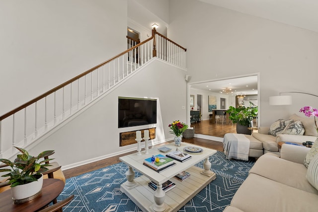 living room featuring wood finished floors, stairway, baseboards, a high ceiling, and recessed lighting