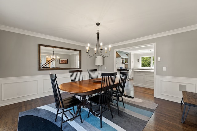 dining area featuring crown molding, an inviting chandelier, dark wood finished floors, and a wainscoted wall