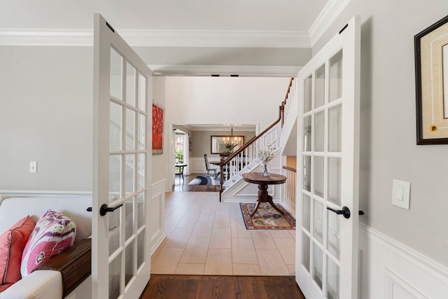 entrance foyer featuring french doors, crown molding, wood finished floors, and a notable chandelier