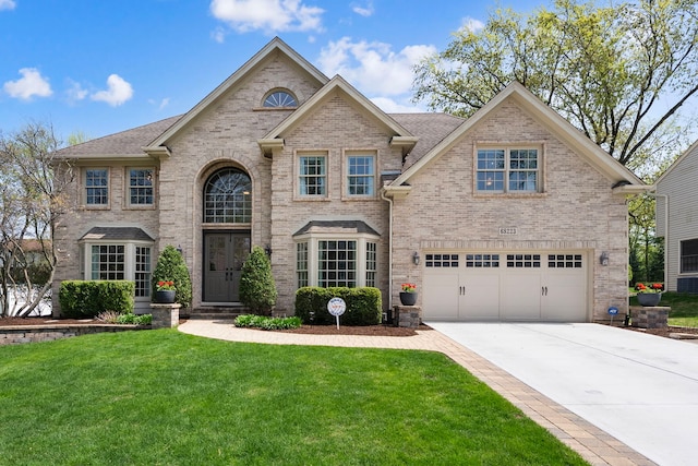 french country style house with a front yard, brick siding, concrete driveway, an attached garage, and a shingled roof