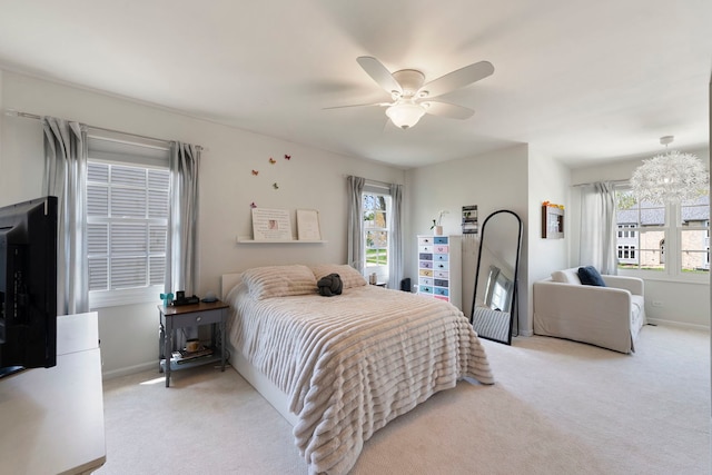 bedroom featuring baseboards, light carpet, and ceiling fan with notable chandelier