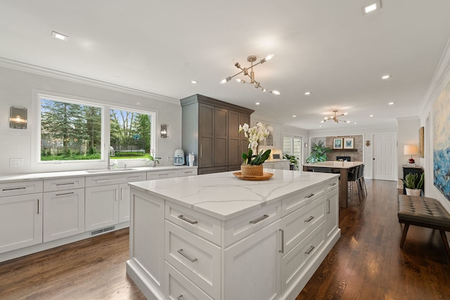 kitchen with visible vents, ornamental molding, a center island, tasteful backsplash, and a sink
