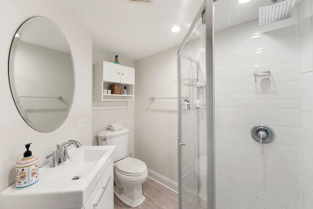 bathroom featuring vanity, wood finished floors, toilet, baseboards, and a stall shower