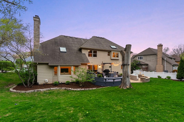 back of property with fence, a yard, a wooden deck, and an outdoor living space