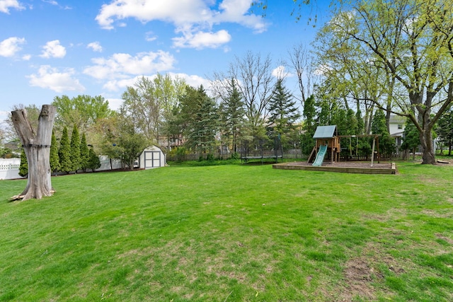 view of yard featuring a playground, a shed, an outbuilding, and fence