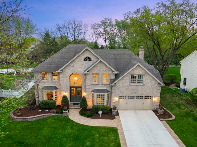 view of front of house with a garage, a front yard, a chimney, brick siding, and driveway