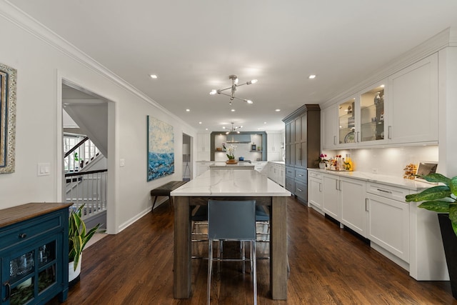 kitchen featuring ornamental molding, a kitchen island, glass insert cabinets, dark wood-type flooring, and white cabinets