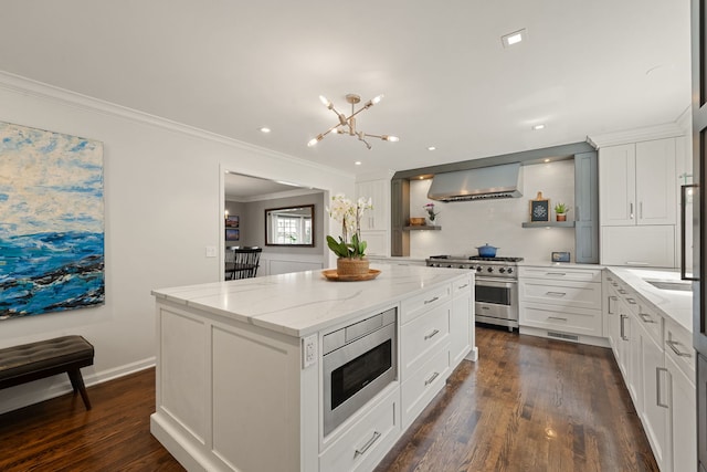 kitchen featuring a kitchen island, light stone countertops, white cabinets, stainless steel appliances, and wall chimney exhaust hood