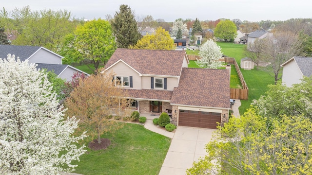view of front of house featuring a front lawn, covered porch, roof with shingles, an attached garage, and driveway