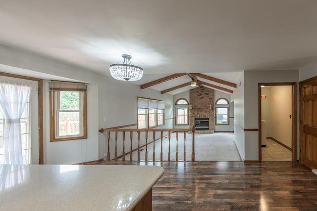interior space featuring decorative light fixtures, a fireplace, wood finished floors, a chandelier, and vaulted ceiling with beams