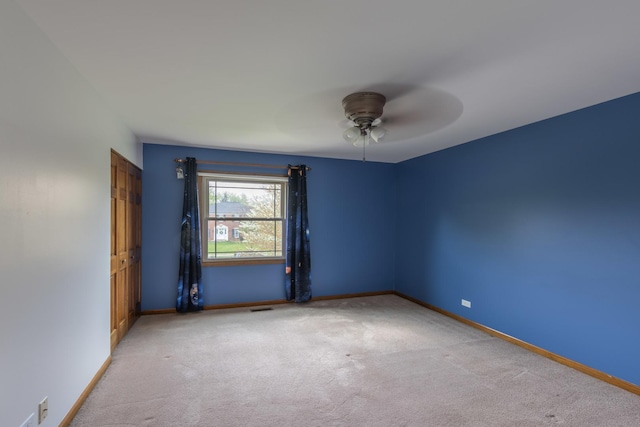 carpeted empty room featuring baseboards, ceiling fan, and visible vents