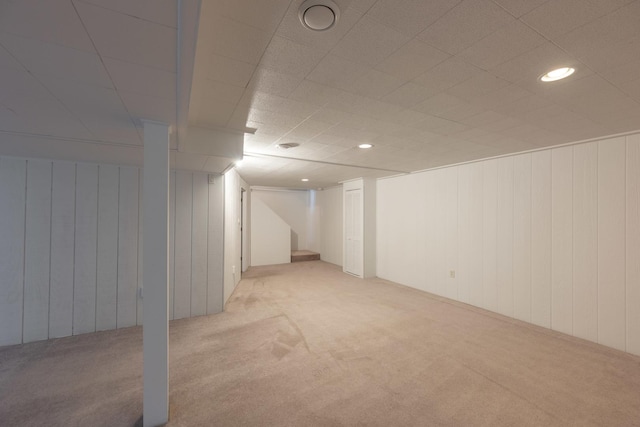 finished basement featuring stairs and light colored carpet