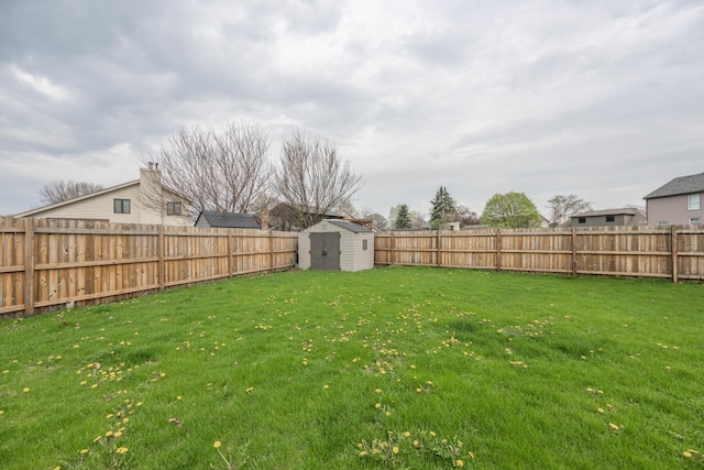 view of yard with a fenced backyard, a shed, and an outbuilding