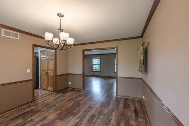 empty room featuring crown molding, dark wood-type flooring, a chandelier, and visible vents