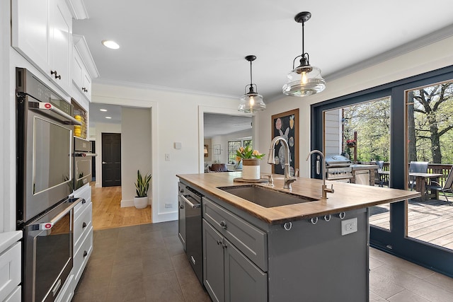 506 Aberdeen Rd, Frankfort, IL 60423 - kitchen with butcher block counters, a sink, appliances with stainless steel finishes, white cabinetry, and an island with sink