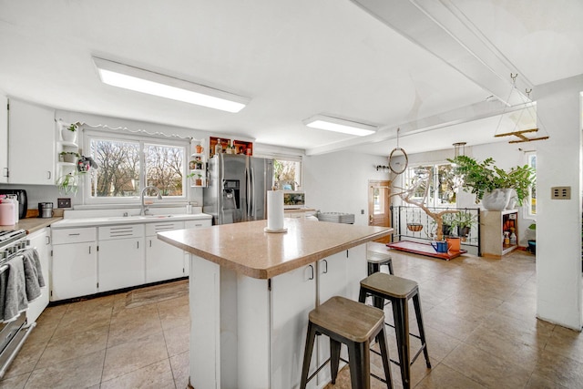 824 Rowlett Ave, Melrose Park, IL 60164 - kitchen with a center island, a sink, light countertops, appliances with stainless steel finishes, and a kitchen breakfast bar