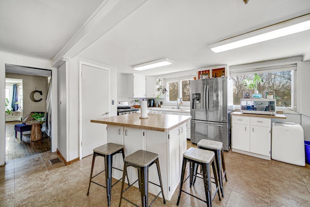 824 Rowlett Ave, Melrose Park, IL 60164 - kitchen with white cabinets, visible vents, a kitchen bar, appliances with stainless steel finishes, and a baseboard radiator