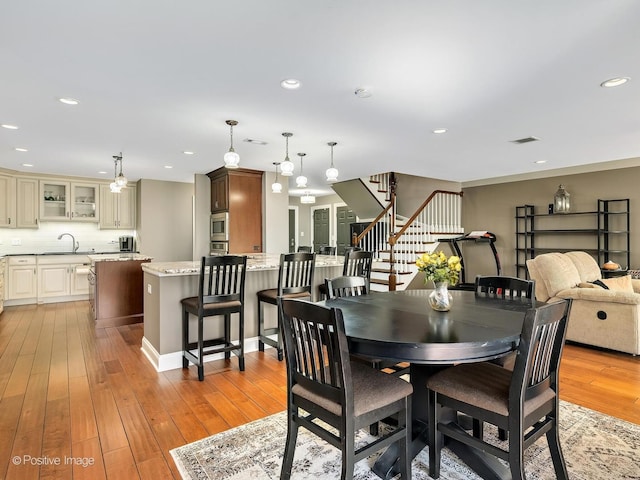 dining room featuring stairway, recessed lighting, and light wood-style flooring